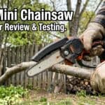 Person using a mini chainsaw to cut a tree branch outdoors in a garden setting.