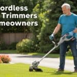 Elderly man using a cordless string trimmer in a lush garden.