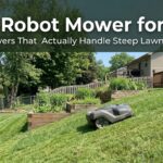Robot mower on a sloped lawn with a person in the background.