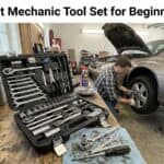 Mechanic working on car with tool set and open hood in garage.