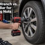 Person using impact wrench on car's lug nut in garage setting.