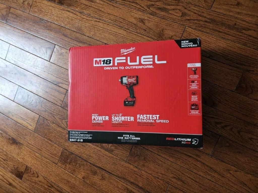 Milwaukee M18 FUEL impact wrench kit on wooden floor.