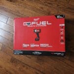 Milwaukee M18 FUEL impact wrench kit on wooden floor.