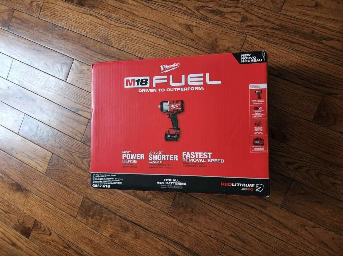 Milwaukee M18 FUEL impact wrench kit on wooden floor.