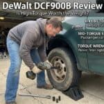 Man using impact wrench to change car tire in garage setting.